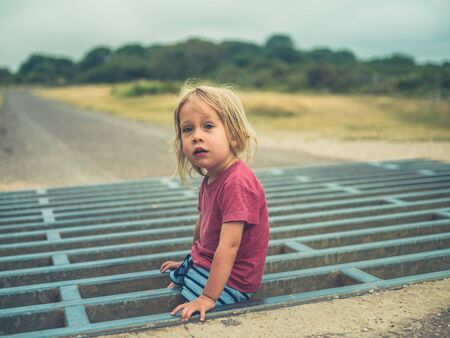 A little toddler is playing on a cattle gridの写真素材