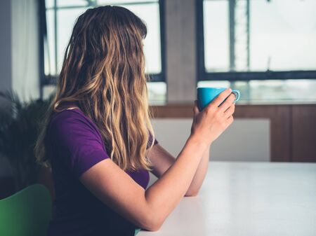 A young woman is drinking coffee in a city apartmentの写真素材