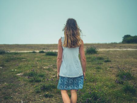 A young woman is walking in a meadow on a foggy dayの写真素材