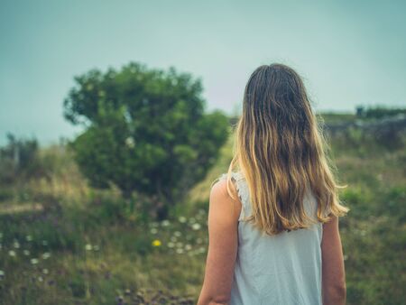 A young woman is walking in a meadow on a foggy dayの写真素材