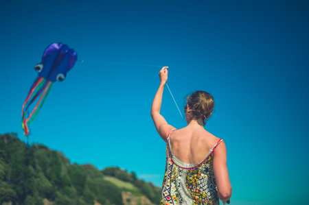 A young woman is flying a kite on the beach in summerの写真素材