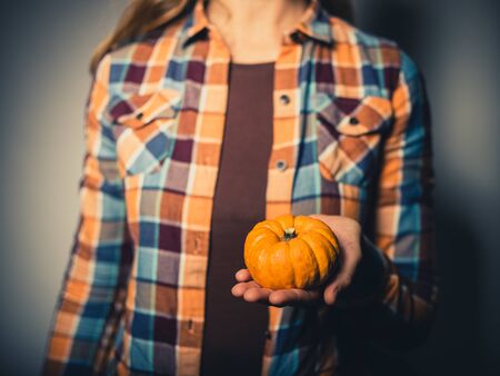 Studio shot of a young woman holding a small pumpkinの写真素材