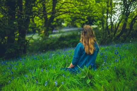 A young woman is relaxing in a meadow of bluebells in the springの写真素材