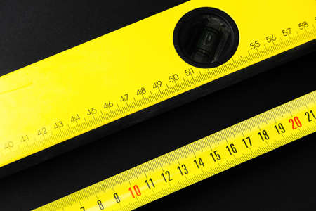 measuring tape and construction level in yellow on a black backgroundの写真素材
