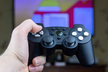 a man holds a wireless gamepad from a video game console in his hand