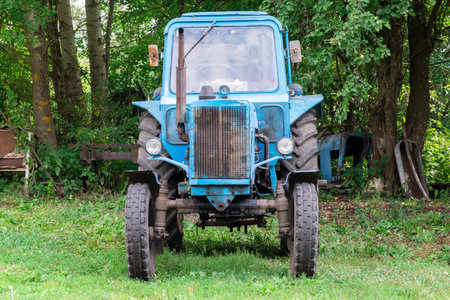 an old blue tractor is standing on the grass after work
