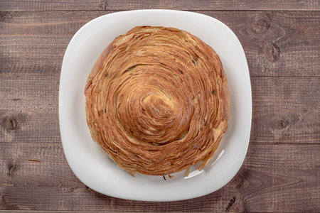 Sweet cinnamon bun roll swirl in glass plate on wooden table