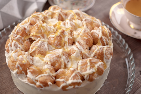 Cake in glass plate, napkin, butter dish and cup of tea on wooden tableの写真素材