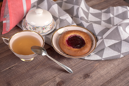 Cake in white plate, napkin, butter dish, spoon and cup of tea on wooden tableの写真素材