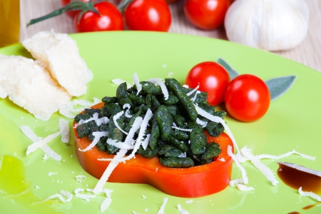 Spatzle small dumplings with spinach and tomatoes on a dishの写真素材