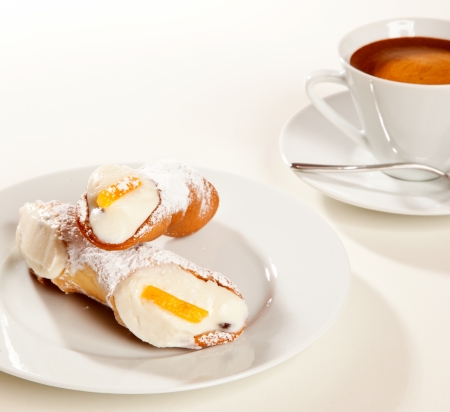 A couple of sicilian cannoli with a coffee cupの写真素材