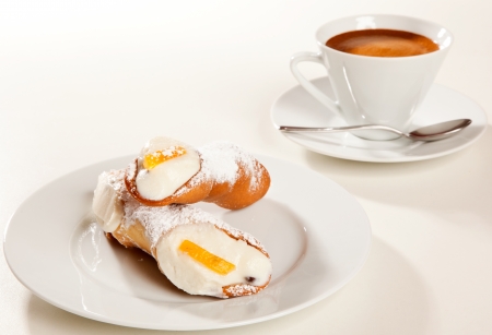 A couple of sicilian cannoli with a coffee cupの写真素材