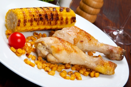 chicken thigh with a boundary of corn cob and saladの写真素材