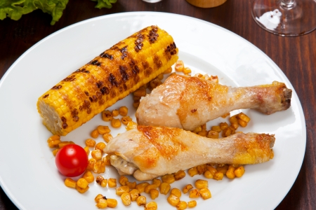 chicken thigh with a boundary of corn cob and saladの写真素材