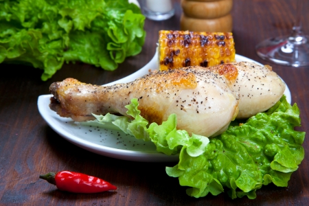 chicken thigh with a boundary of corn cob and saladの写真素材