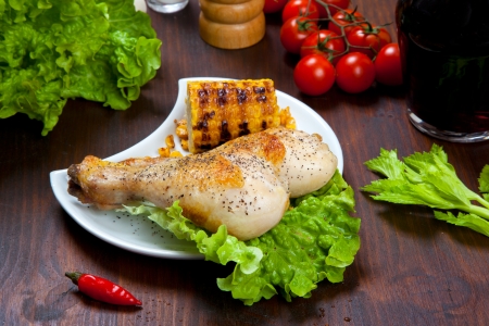 chicken thigh with a boundary of corn cob and saladの写真素材