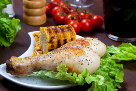 chicken thigh with a boundary of corn cob and saladの写真素材