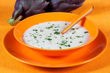 Artichoke vegetarian soup in a dish on a orange tableの写真素材