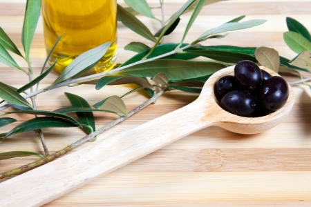 Black olives in a wooden spoonの写真素材