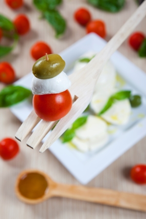 Tomanto, mozzarella and olive on a kitchen forkの写真素材