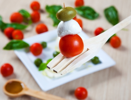 Tomanto, mozzarella and olive on a kitchen forkの写真素材