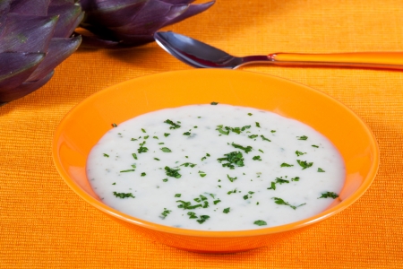 Artichoke vegetarian soup in a dish on a orange tableの写真素材