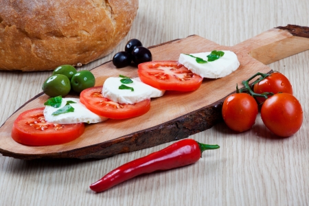 Caprese with olives on a chopping boardの写真素材
