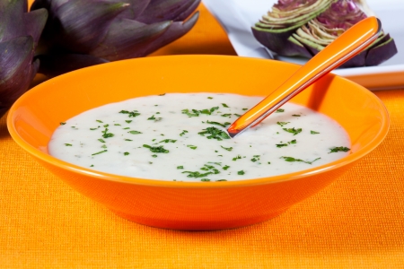 Artichoke vegetarian soup in a dish on a orange tableの写真素材