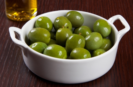 Green olives in a bowl and oilの写真素材