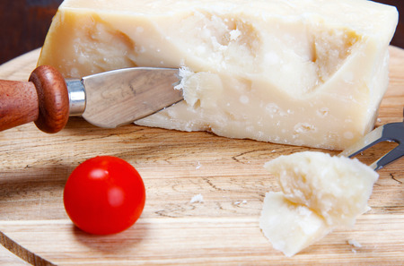 italian cheese on a cutting board and a kitchen knifeの写真素材
