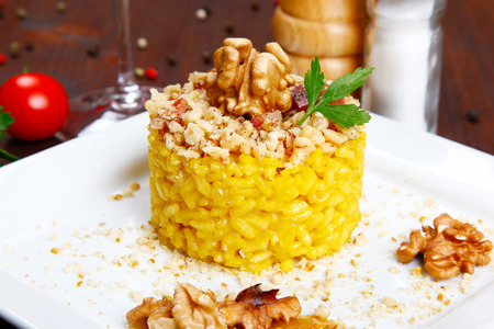 risotto with walnuts, saffron, speck on a dishの写真素材