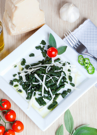 Spatzle small dumplings with spinach and tomatoes on a dishの写真素材