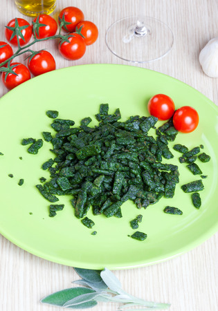 Spatzle small dumplings with spinach and tomatoes on a dishの写真素材