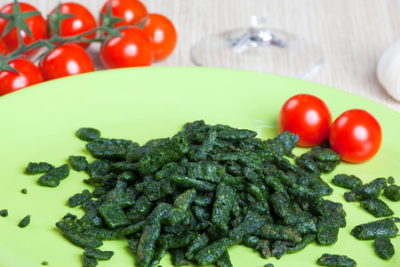Spatzle small dumplings with spinach and tomatoes on a dishの写真素材