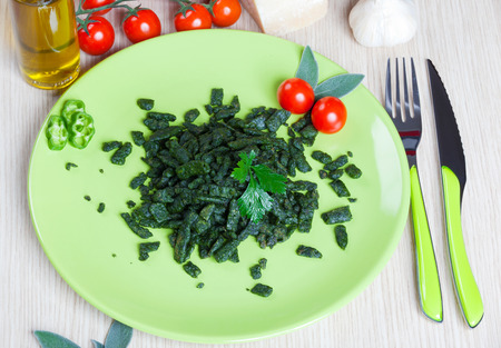 Spatzle small dumplings with spinach and tomatoes on a dishの写真素材