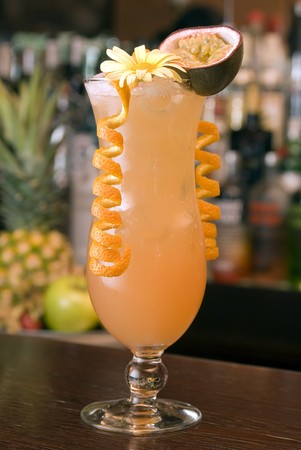 Tropical Cocktail in a hurricaneglass with a blossom, passion fruit and orange paringの写真素材