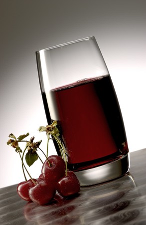 Cherry juice with a bunch of cherrsy on polished aluminum surface.の写真素材