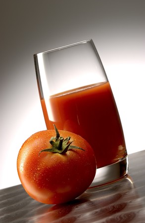 Tomato juice with a whole tomato on polished aluminum surface.の写真素材