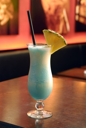 swimmingpool cocktail with a piece of pineapple and a black strawの写真素材