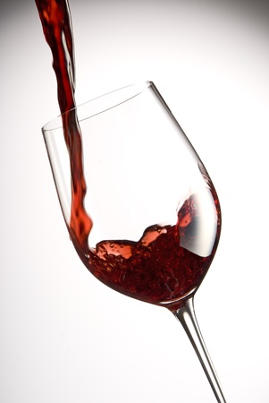 pour red wine into a glass with white backgroundの写真素材