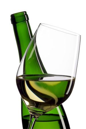 glass of white wine in front of a green white wine bottle and white backgroundの写真素材