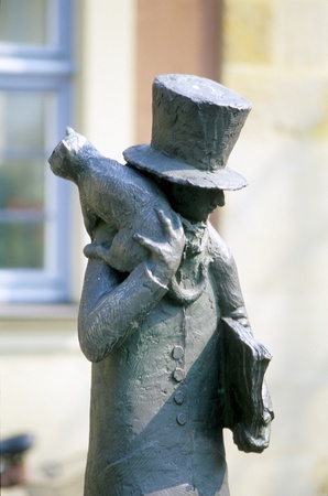 sculpture of a men with hat and a cat on his sholder placed in Bambergの写真素材