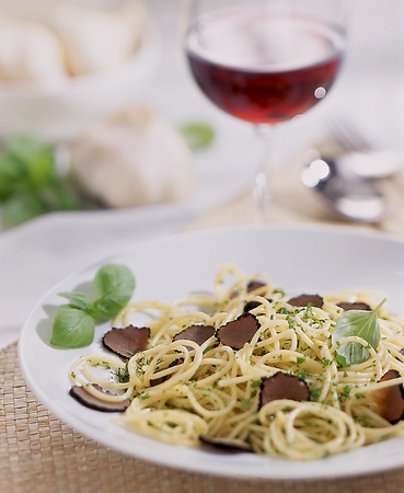 plate with pasta and truffle and a glass of red wine in the backgroundの写真素材