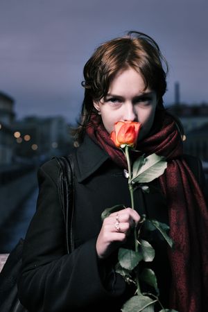 Portrait of a young redhead woman with fresh red rose in St. Petersburg, Russia.の写真素材