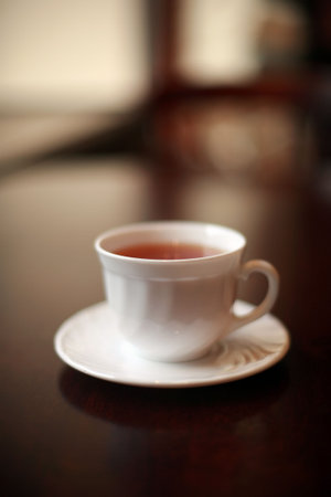 A white cup of tea on a glossy table. Shallow DOF.の写真素材