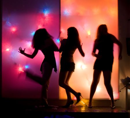 Dancing girls silhouettes in front of colorful disco lightsの写真素材