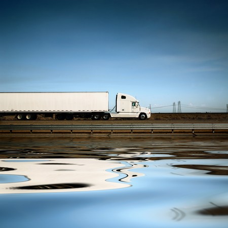 White freight truck driving on freeway under blue sky.の写真素材