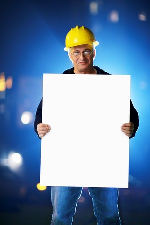 Construction worker holding blank white board. Shallow DOF.の写真素材