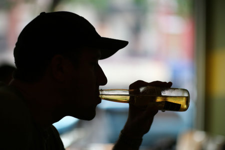 Silhouette of a man drinking bear. Close-up.