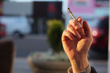 Hand with smoking cigarette. Close-up, shallow DOF.の写真素材